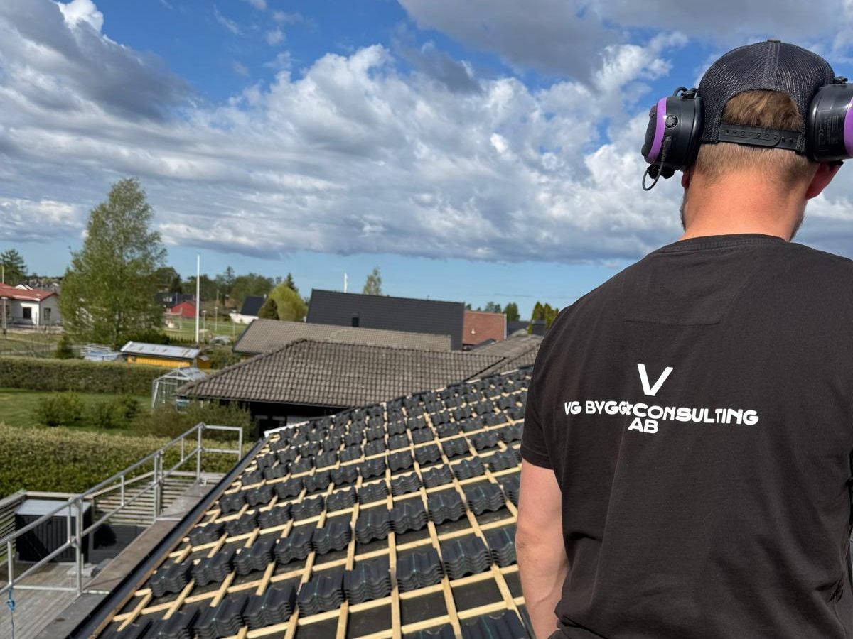 En av oss på ett tak mitt i en takläggning, med VG Bygg & Consultings logga på ryggen
